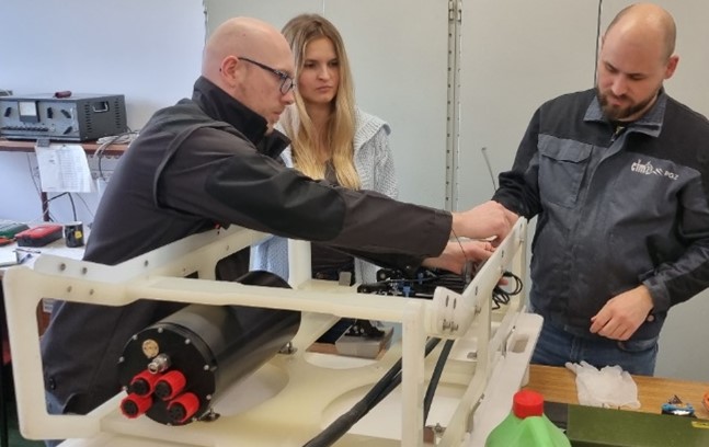 Inżynierowie CTM montujący moduł elektroniczny urządzenia badawczego w laboratorium — logo CTM i PGZ na kurtkach