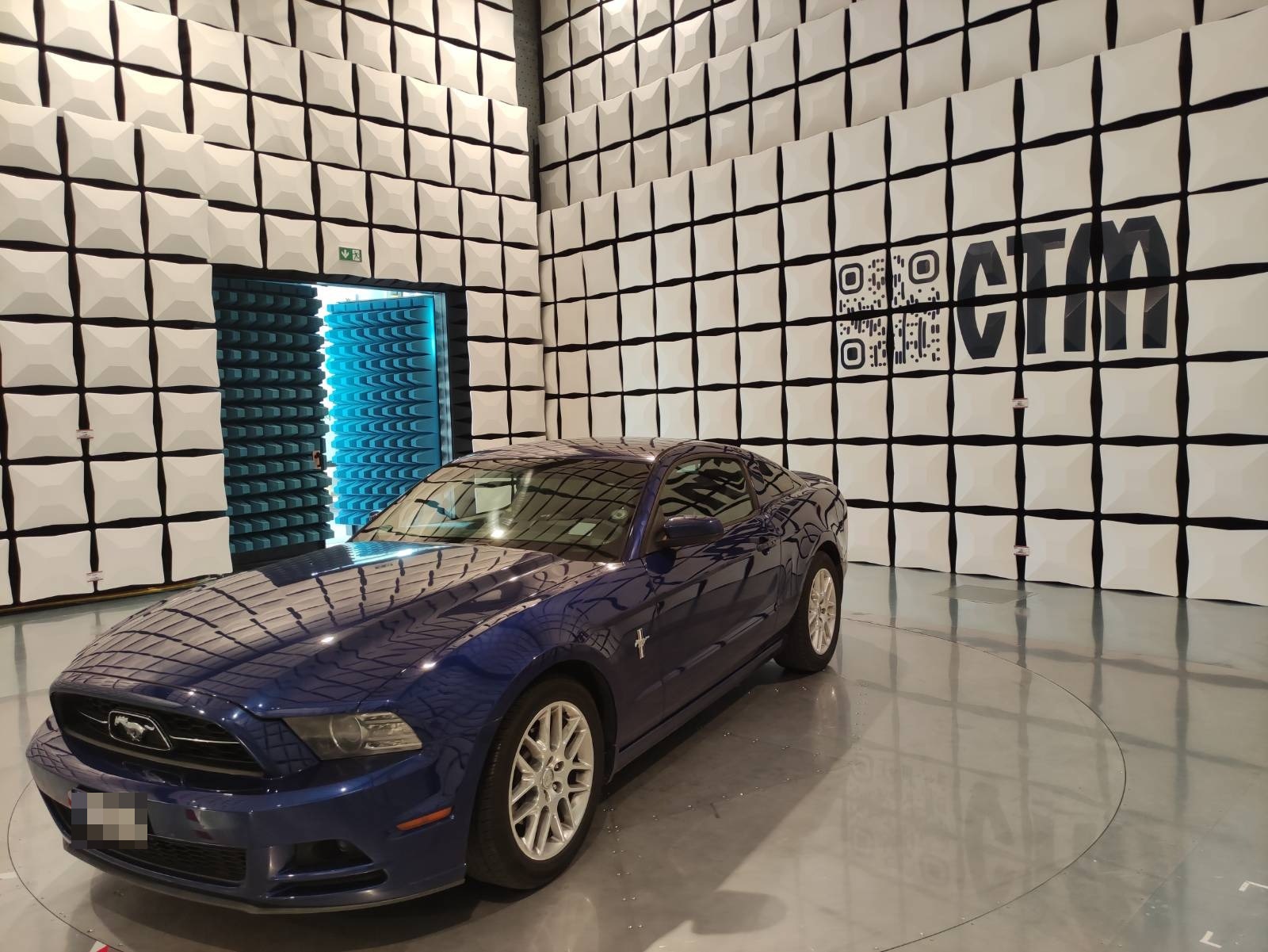 Samochód Ford Mustang na obrotnicy w komorze bezechowej EMC LabNet — logo CTM na ścianie z absorberami