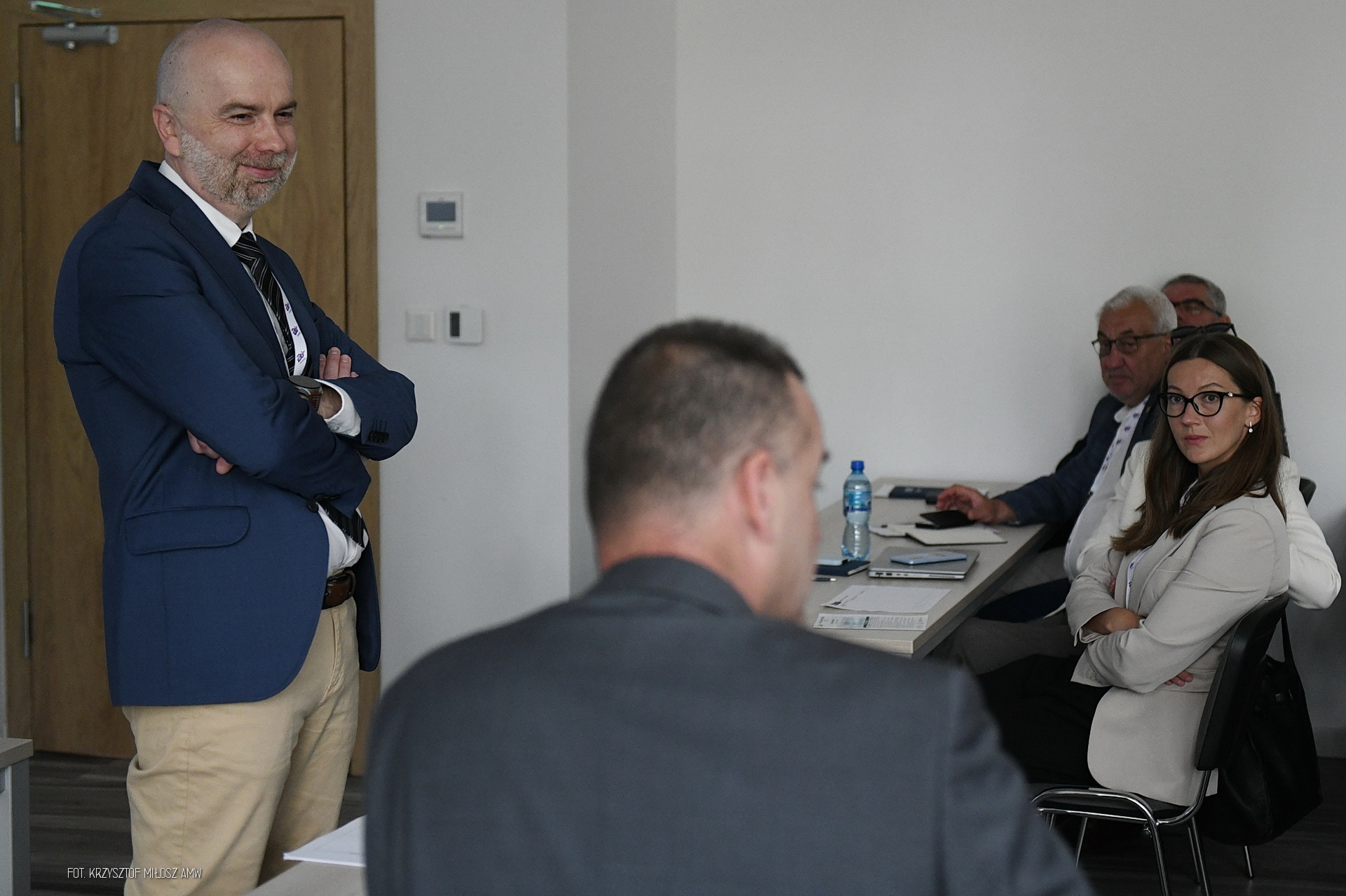 Dyskusja uczestników konferencji Digital Baltic w sali AMW — stojący mężczyzna w niebieskiej marynarce i osoby przy stole konferencyjnym