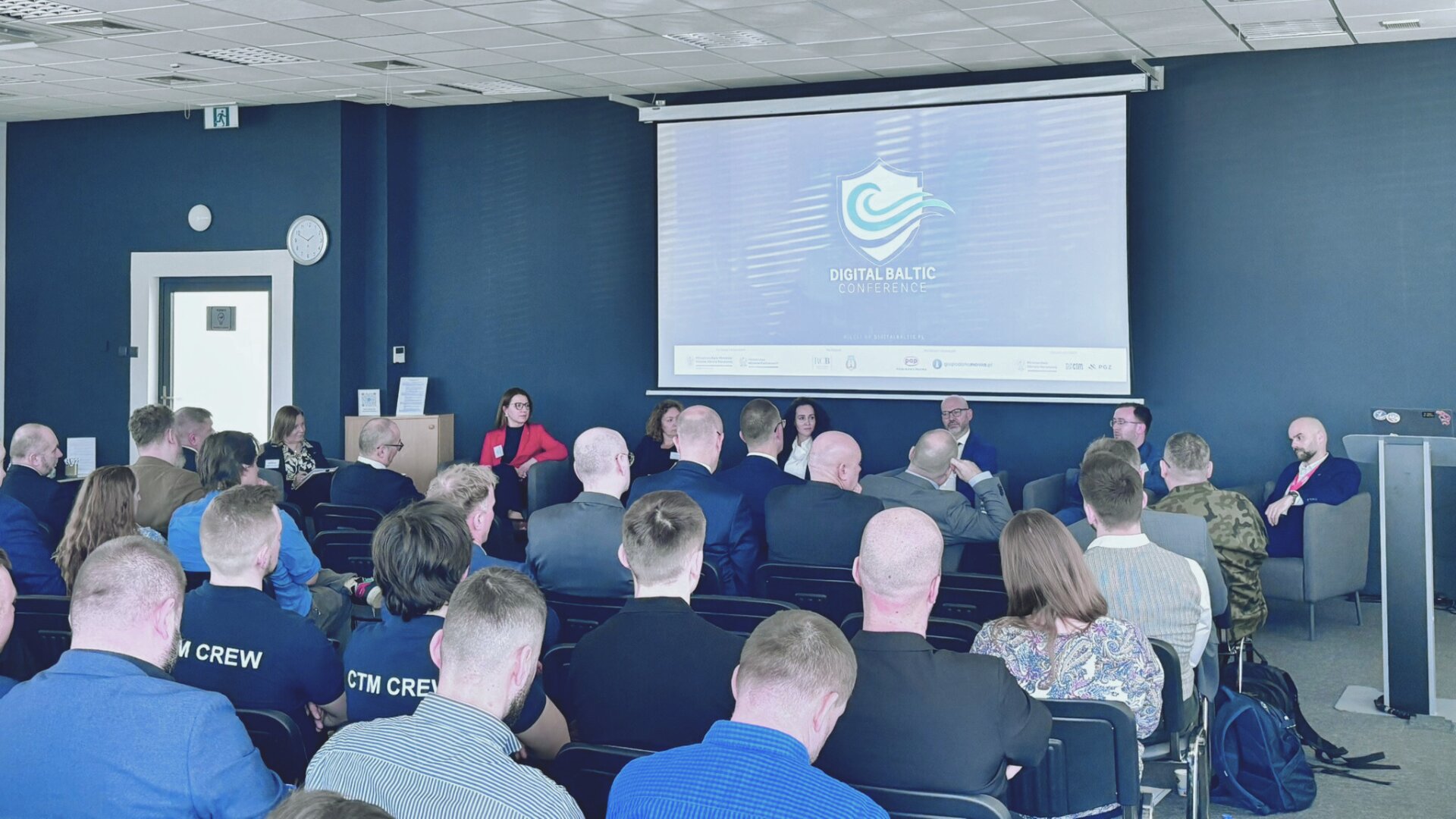 Panel Digital Baltic Conference — prelegenci w fotelach przed ekranem z logo konferencji, widok na salę z uczestnikami CTM CREW