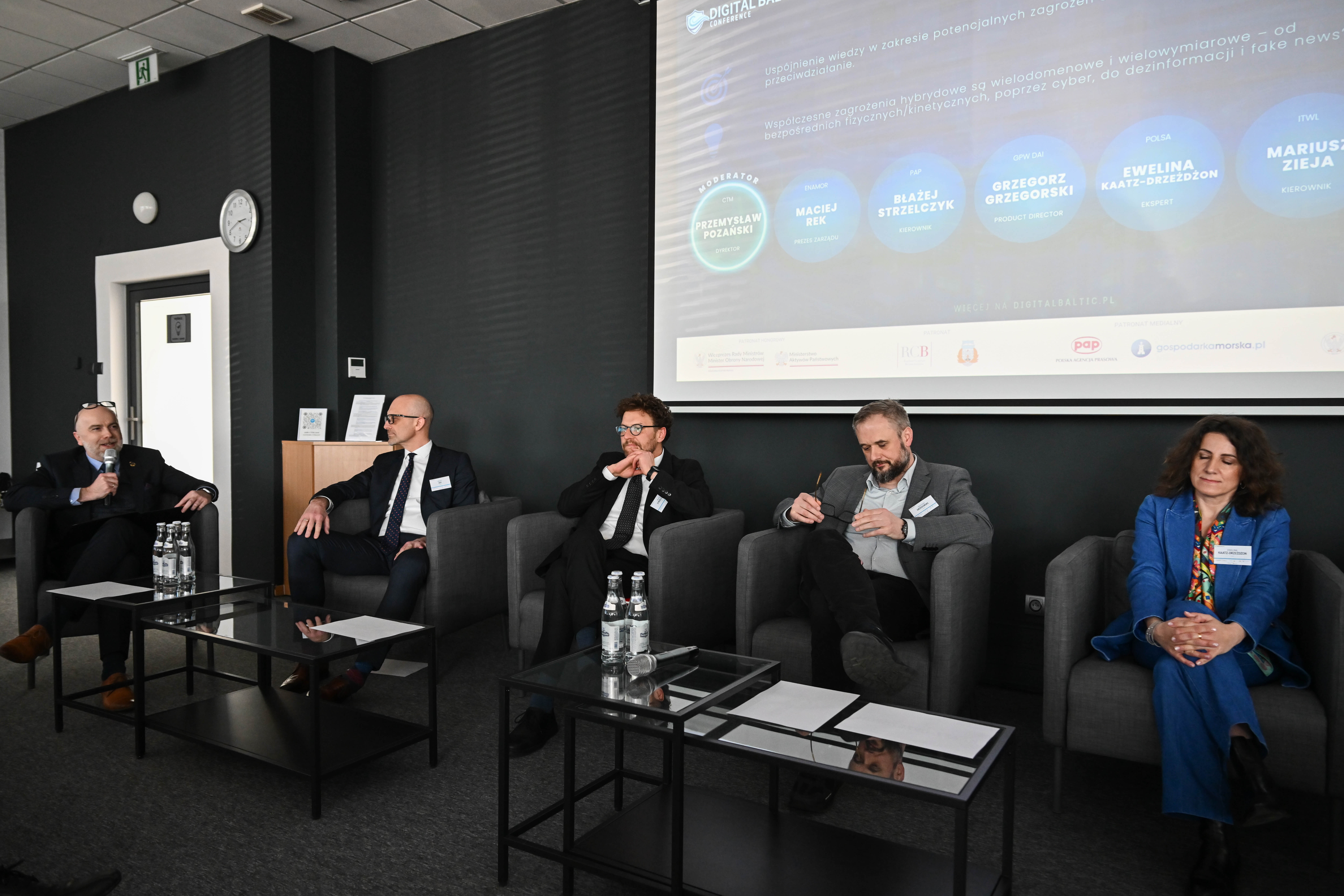 Panel o dezinformacji i fake newsach — pięciu ekspertów w fotelach przed ekranem z nazwiskami prelegentów