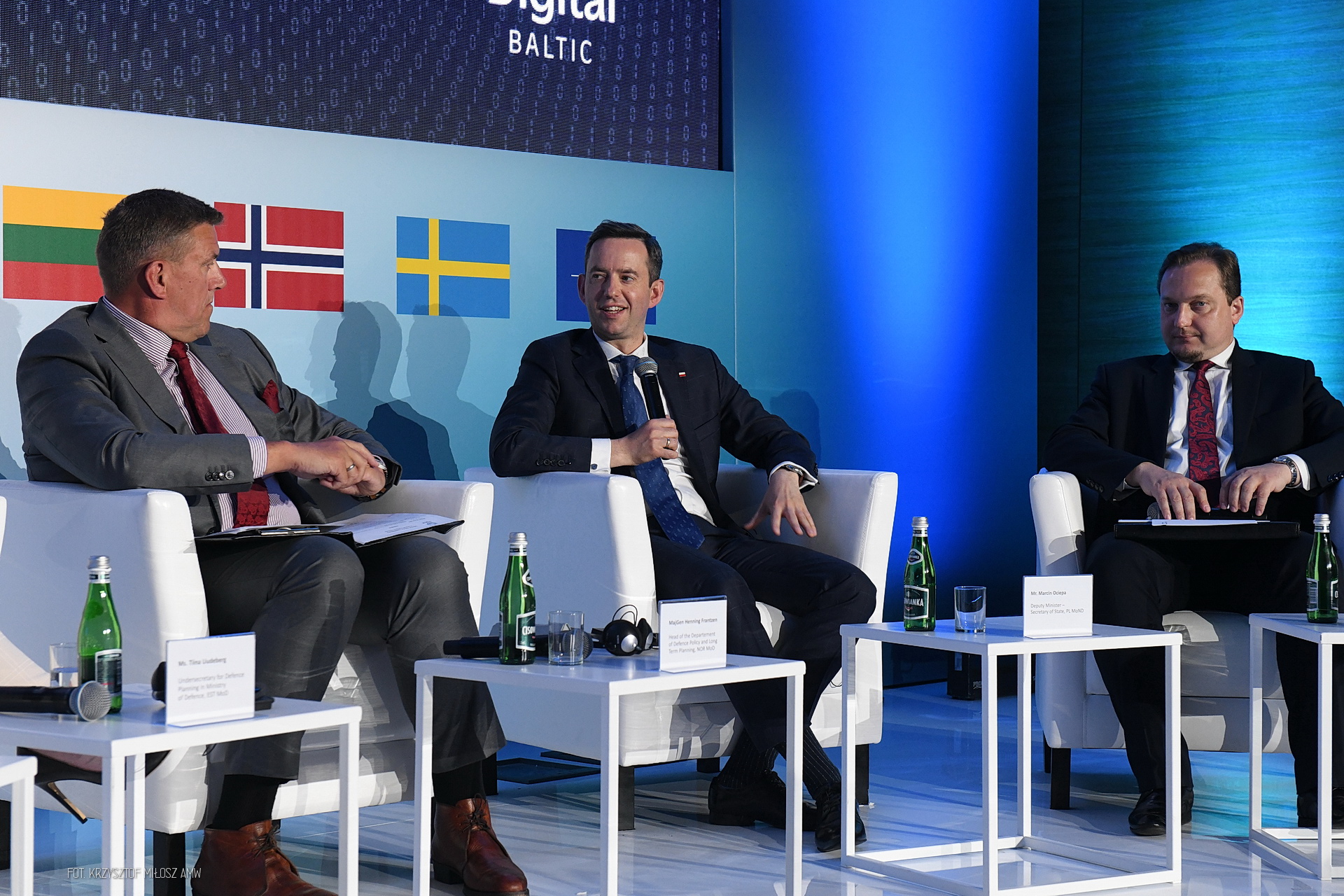 Panel z Marcinem Ociepą i przedstawicielami ministerstw obrony Norwegii i Estonii — flagi Litwy, Norwegii, Szwecji i NATO