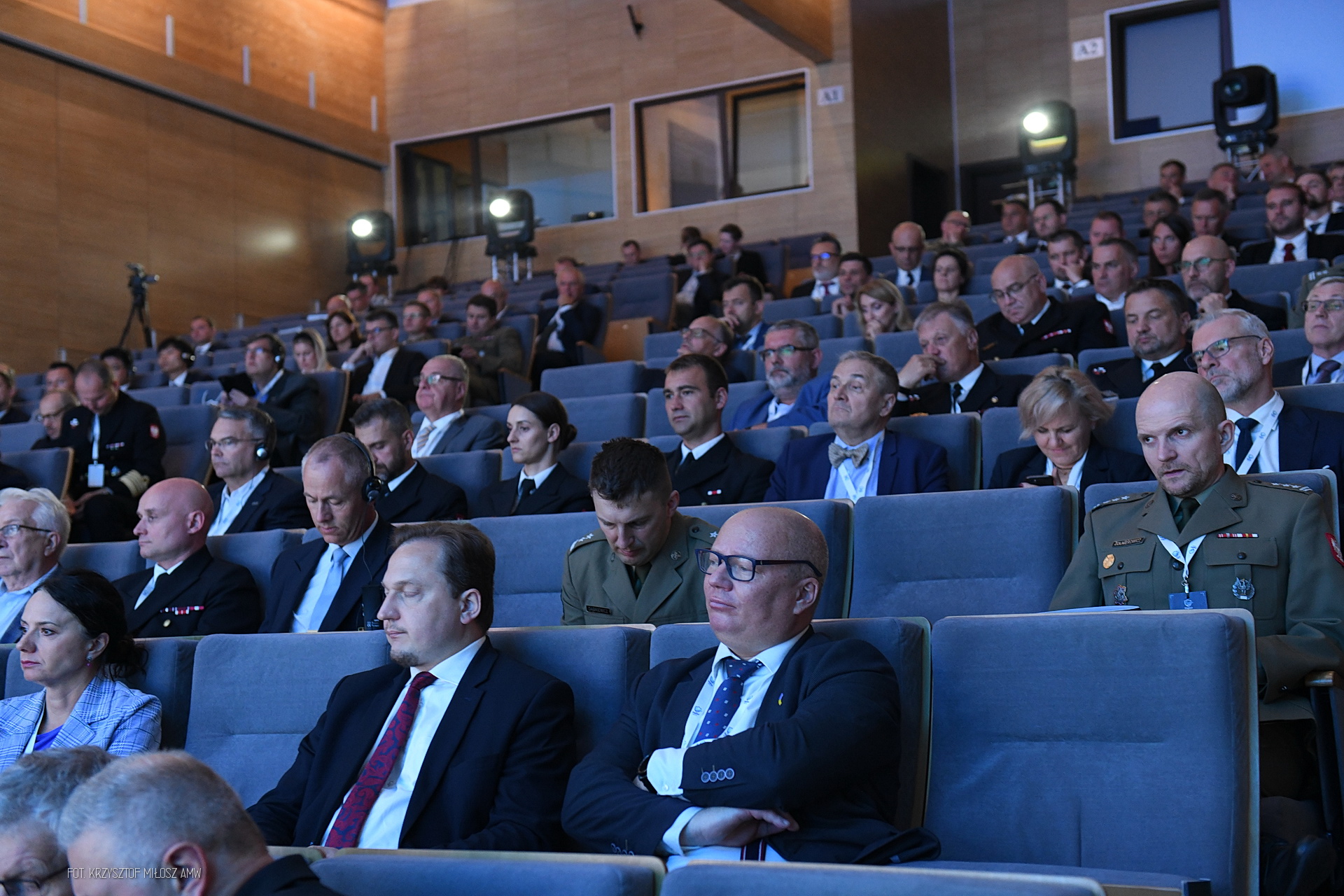 Widownia konferencji Digital Baltic — uczestnicy w mundurach i garniturach z zestawami do tłumaczenia symultanicznego