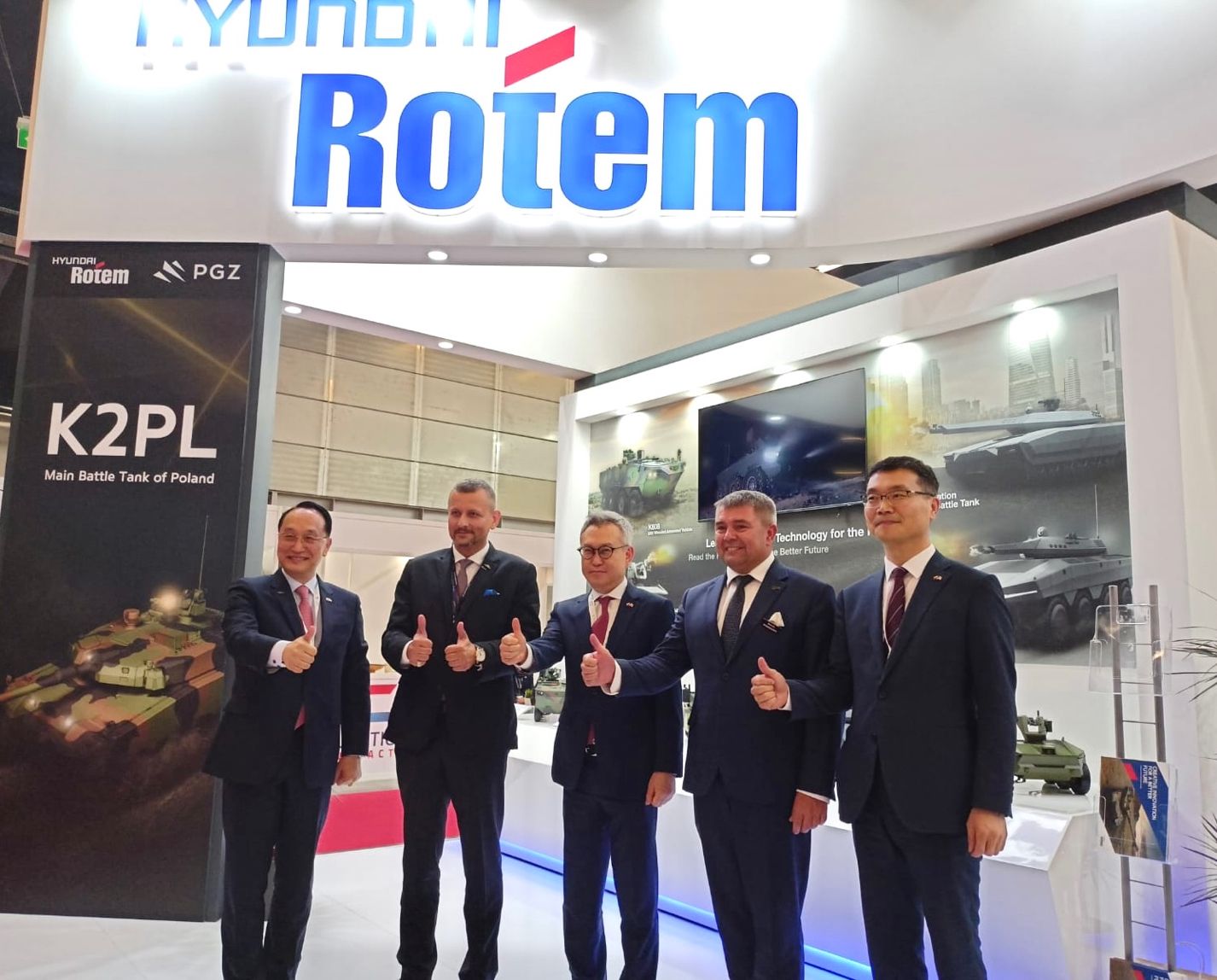 Przedstawiciele Hyundai Rotem i PGZ na stoisku promującym czołg K2PL — gest kciuka w górę