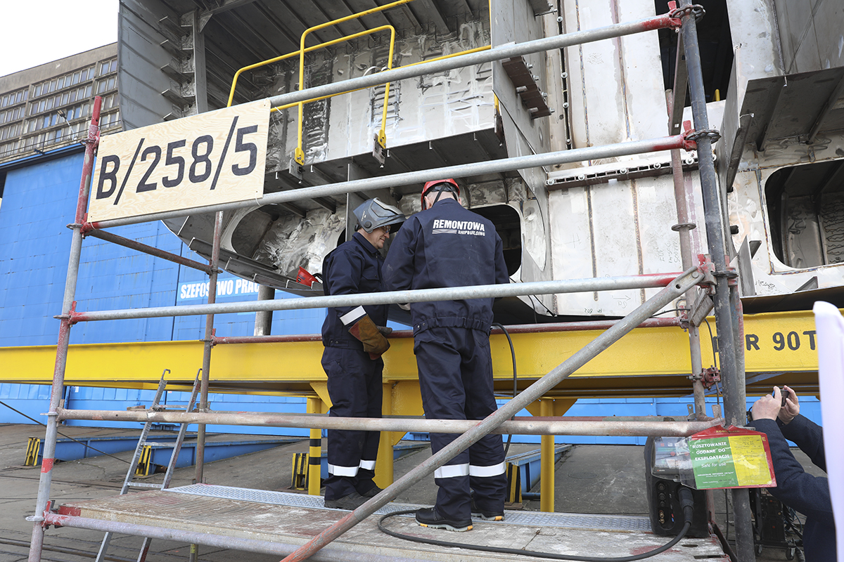 Pracownicy stoczni Remontowa Shipbuilding na rusztowaniu przy stalowej sekcji kadłuba z tabliczką B/258/5