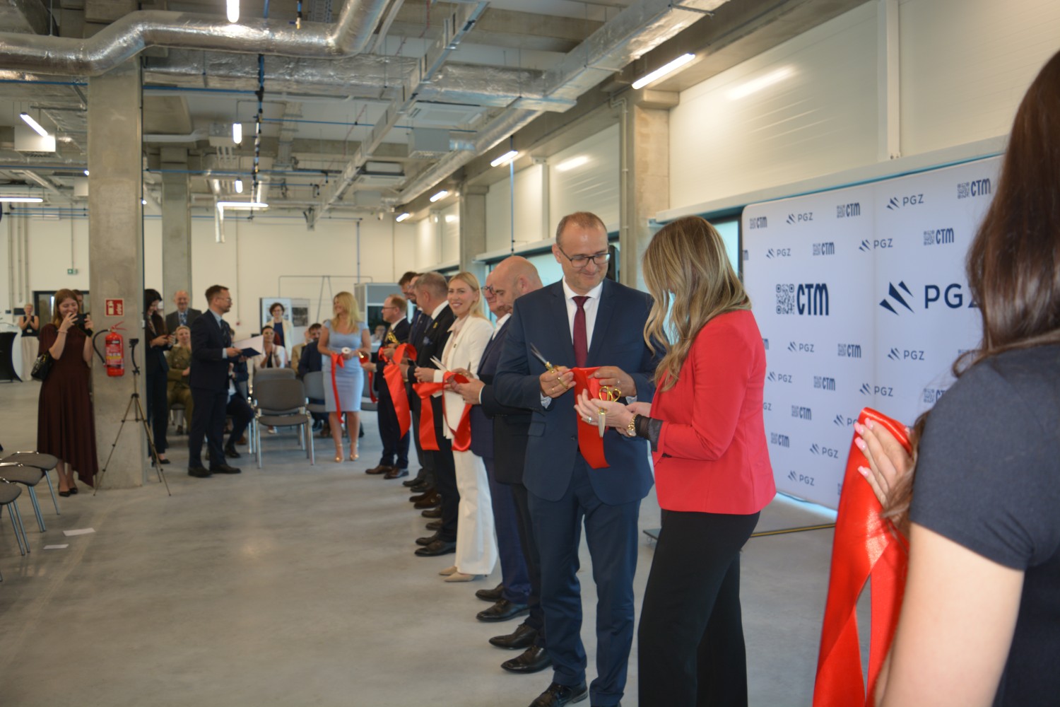 Ceremonialne przecięcie czerwonej wstęgi podczas otwarcia Centrum Elektroniki Militarnej w hali OBR CTM S.A. — przedstawiciele PGZ i zaproszeni goście