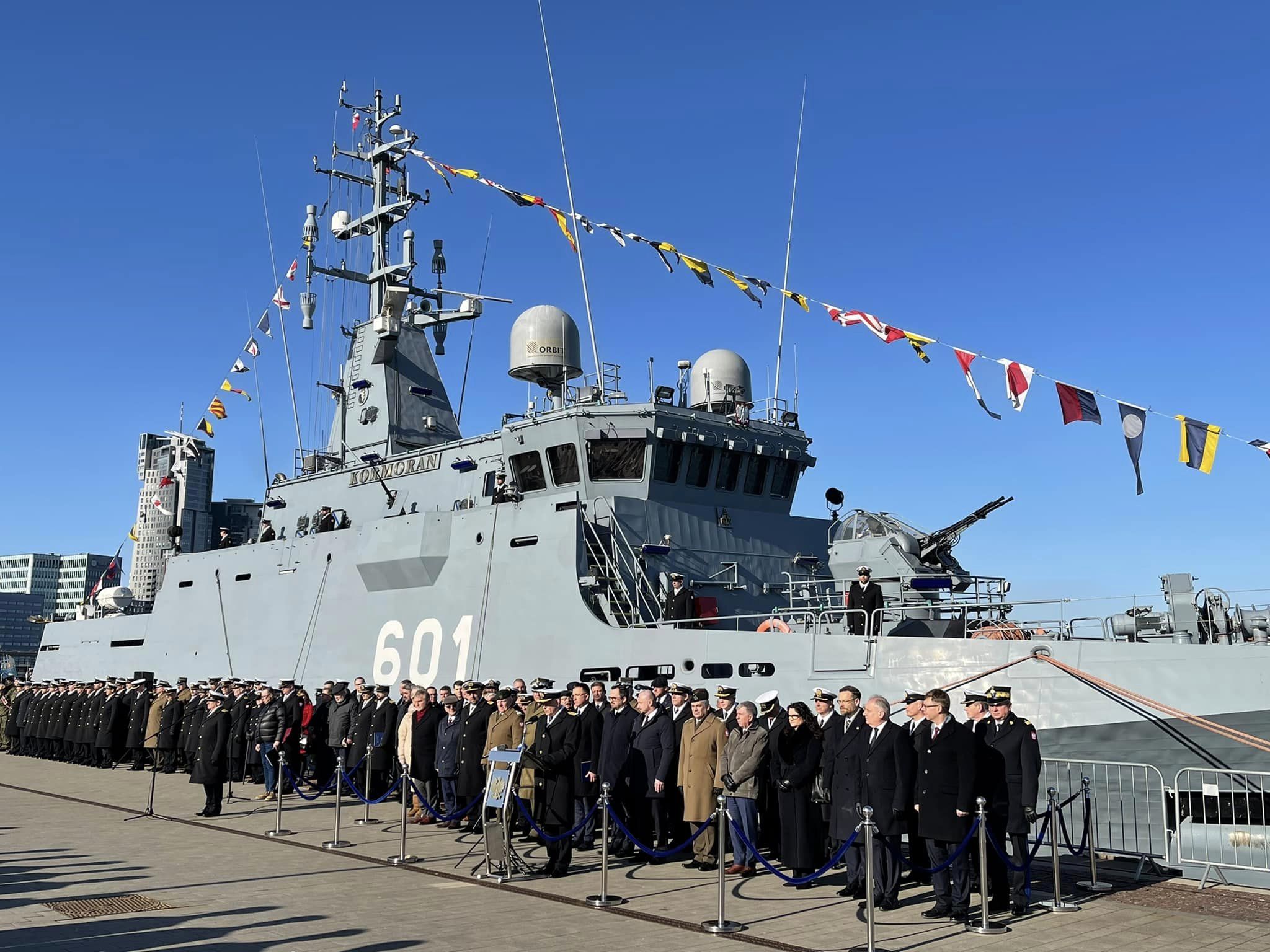 Uroczystość na nabrzeżu przed ORP Kormoran (601) z galą banderową — przedstawiciele wojska i rządu przy mównicy