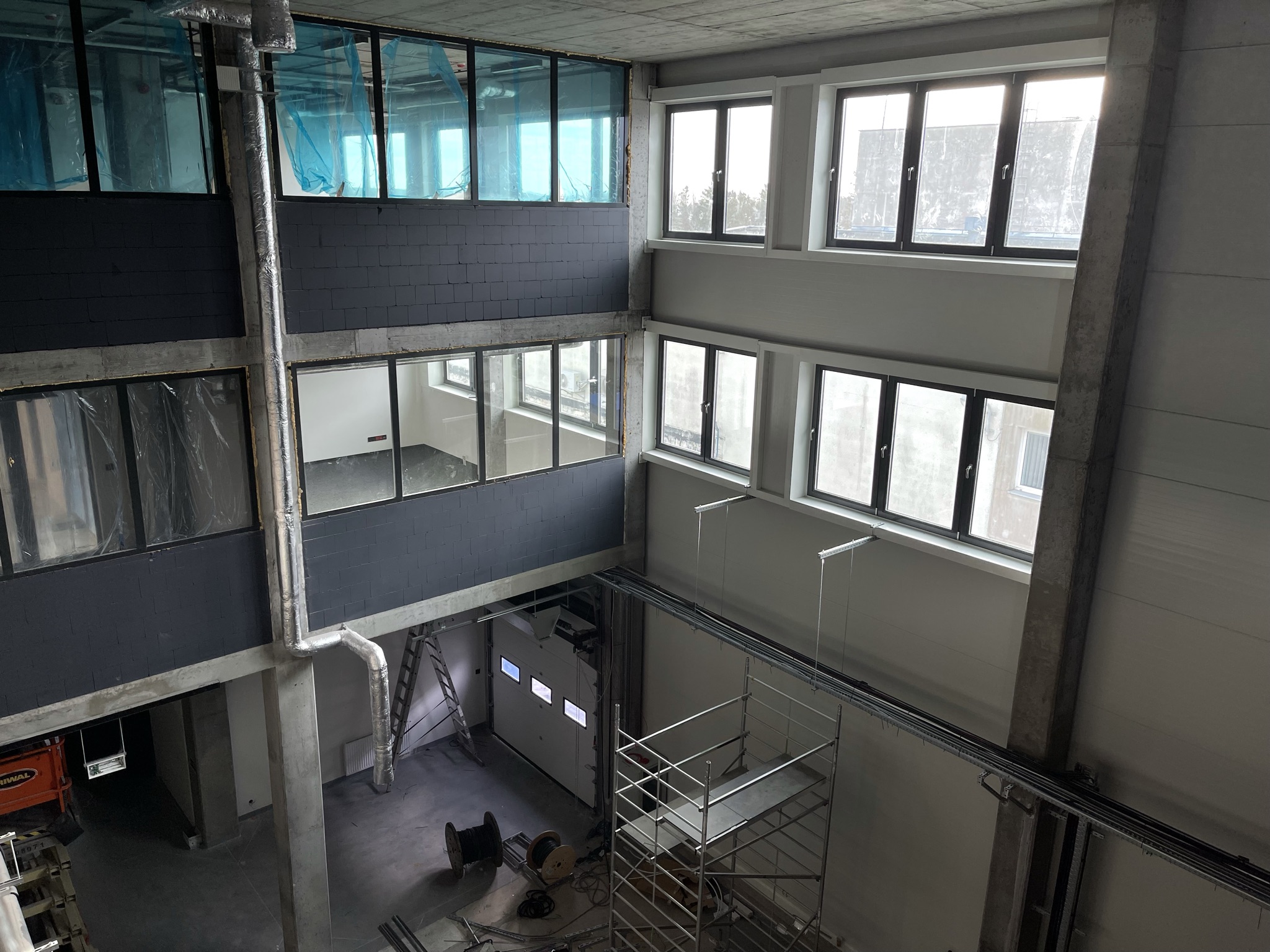 Wnętrze budowanego laboratorium EMC Lab-Net — konstrukcja żelbetowa, okna i rusztowanie na hali wielokondygnacyjnej