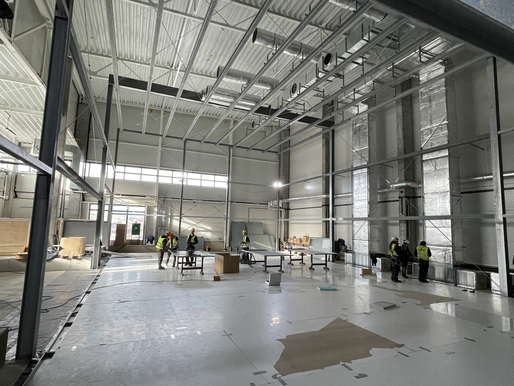 Montaż instalacji wentylacyjnych w wysokiej hali laboratoryjnej EMC Lab-Net — pracownicy w kaskach i kamizelkach