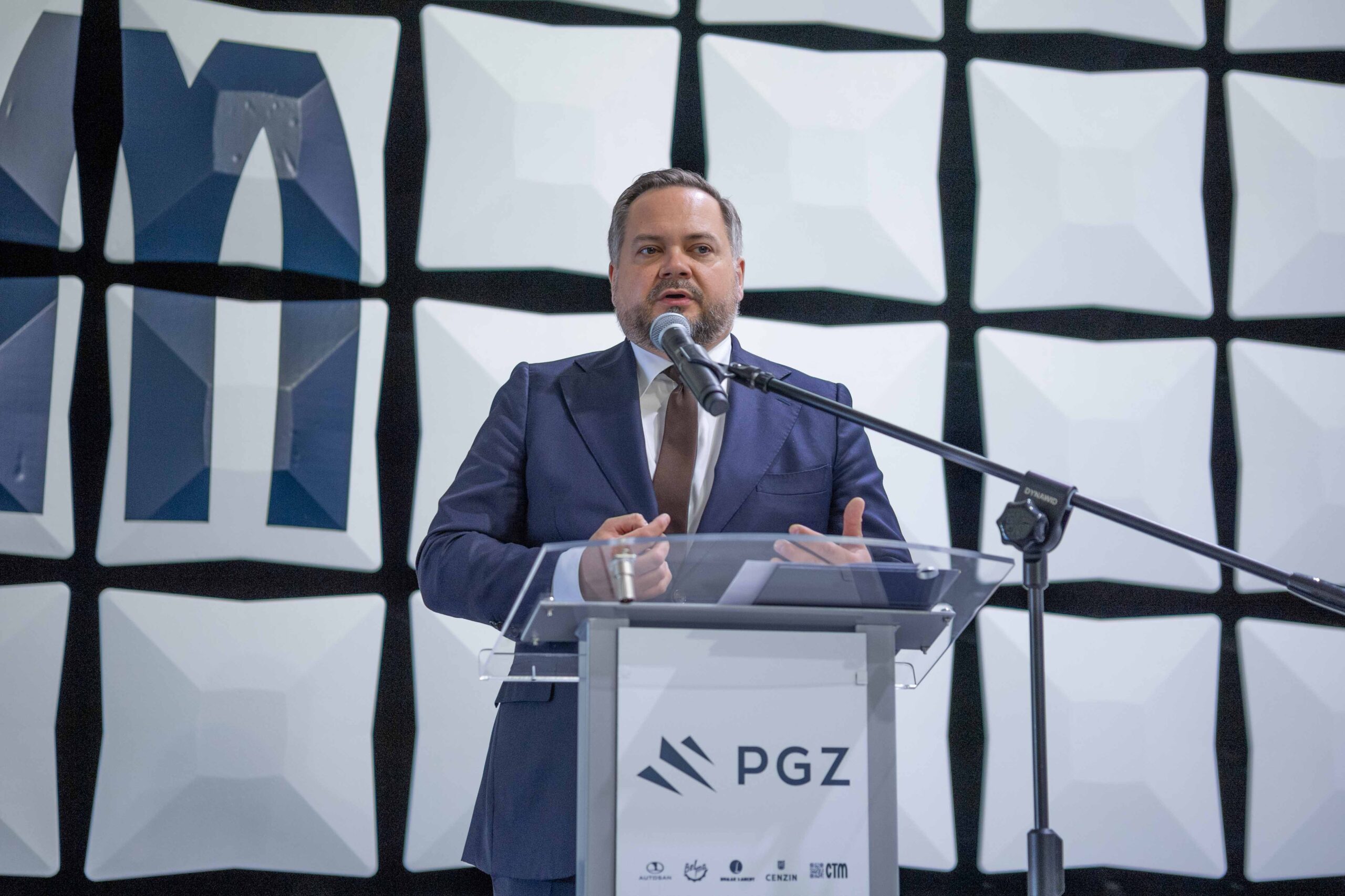 Prezes PGZ przemawia przy mównicy z logo PGZ w komorze bezodbiciowej podczas uroczystości rozpoczęcia budowy CEM