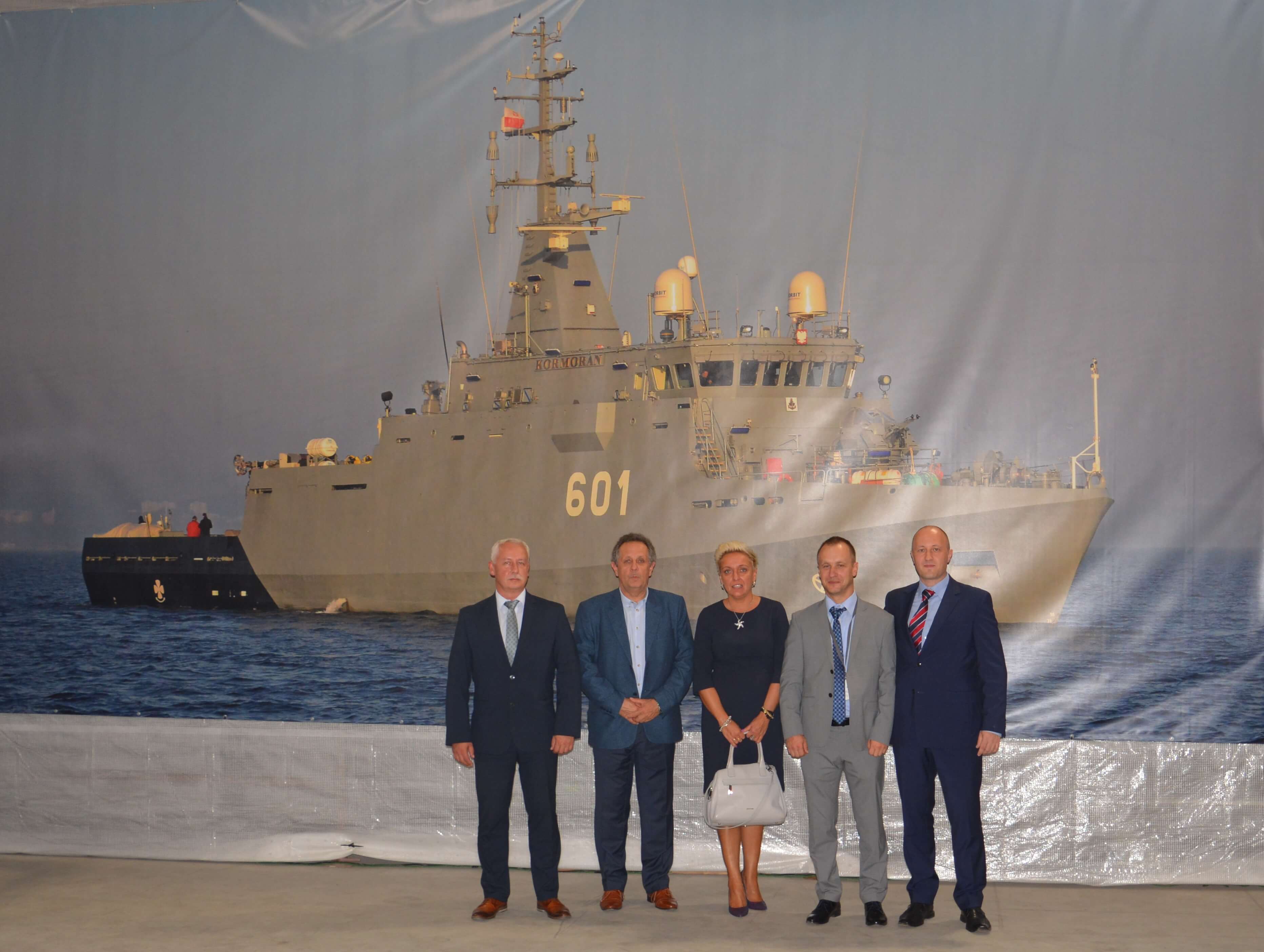 Przedstawiciele konsorcjum przed banerem z ORP Kormoran 601 podczas uroczystości