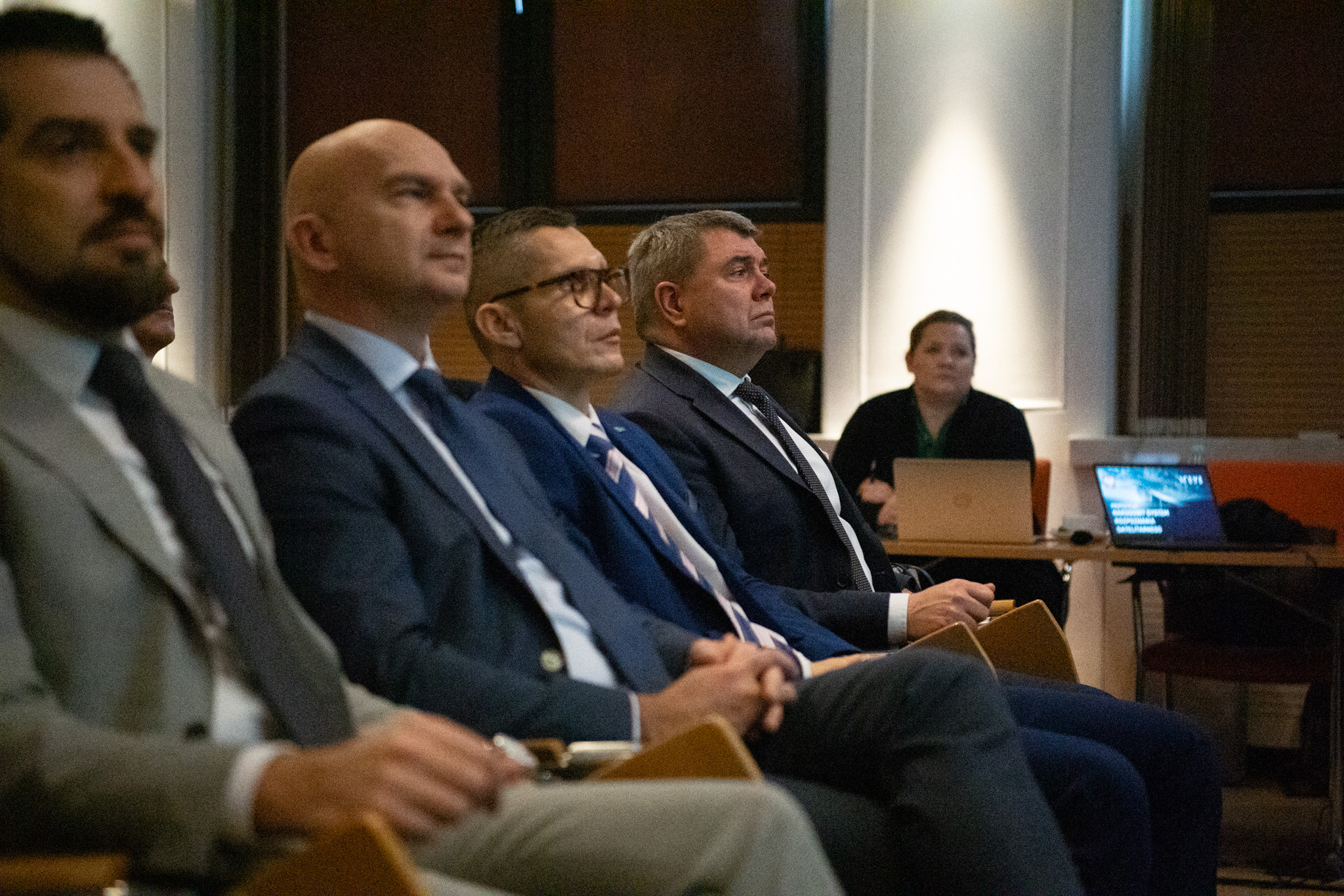 Uczestnicy spotkania roboczego w garniturach, w tle ekran laptopa z tytułem Narodowego Systemu Rozpoznania Satelitarnego