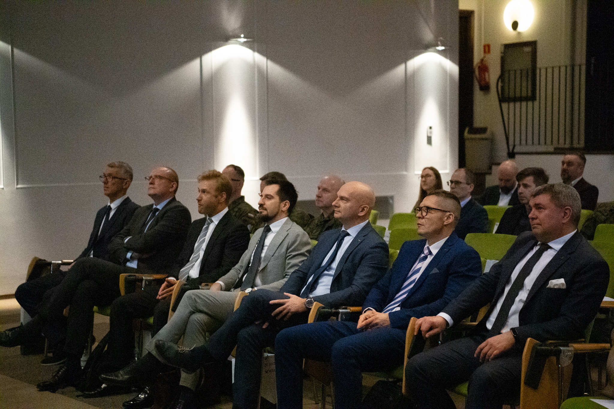 Widownia warsztatów w biurze PGZ — przedstawiciele przemysłu w garniturach i wojskowi w mundurach na zielonych fotelach