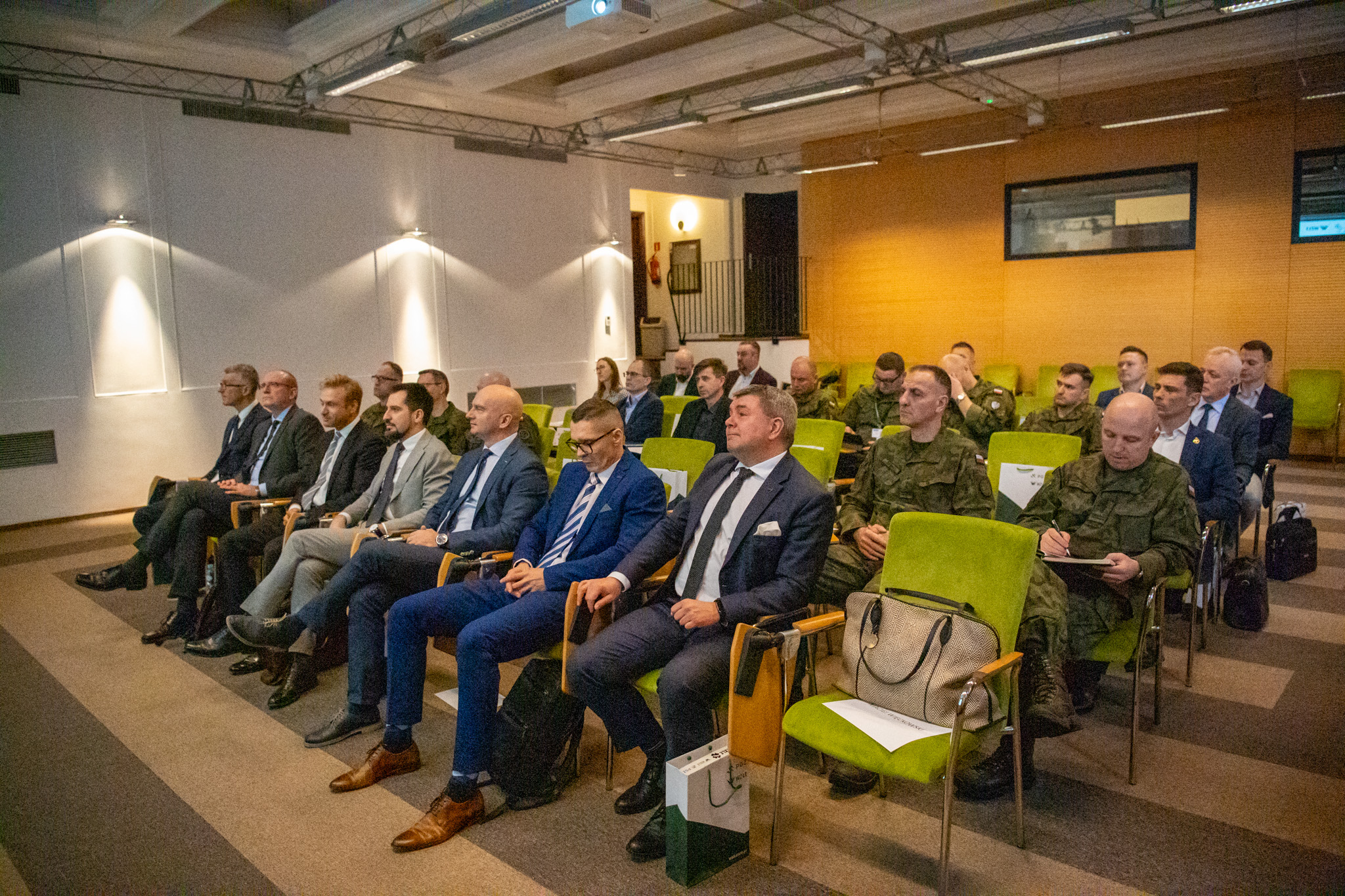 Sala konferencyjna podczas spotkania o systemie rozpoznania satelitarnego — cywile i żołnierze w zielonych fotelach