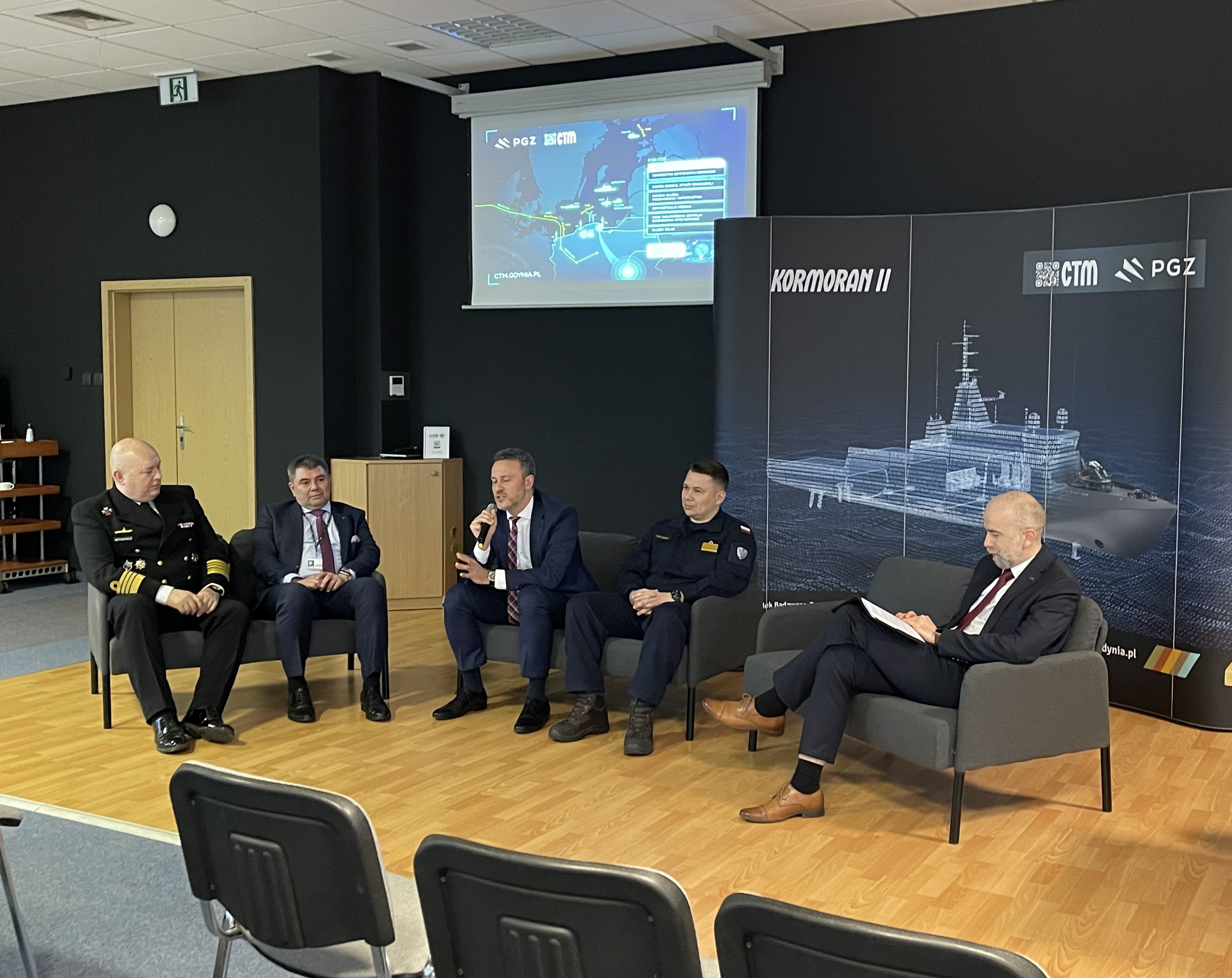 Panel dyskusyjny na forum — uczestnicy przed banerem Kormoran II, ekran z mapą Bałtyku i logotypami CTM oraz PGZ